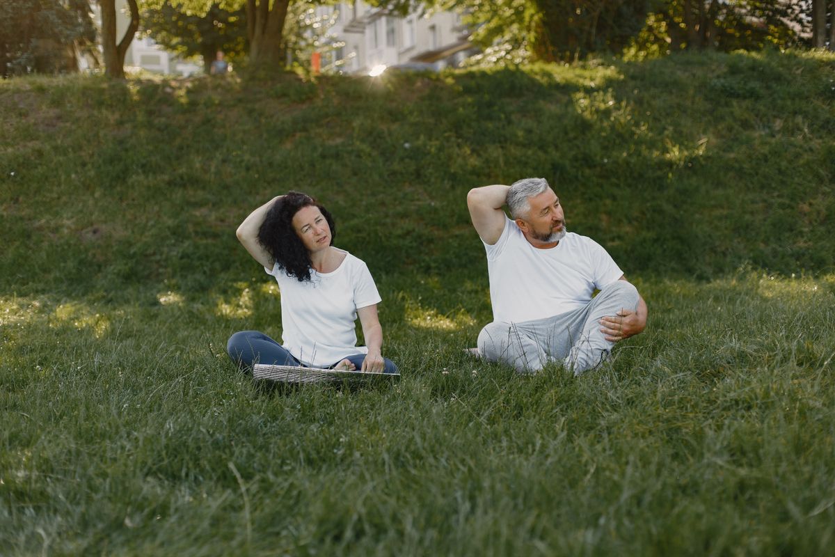 Couple stretching together on the grass in a sunny park